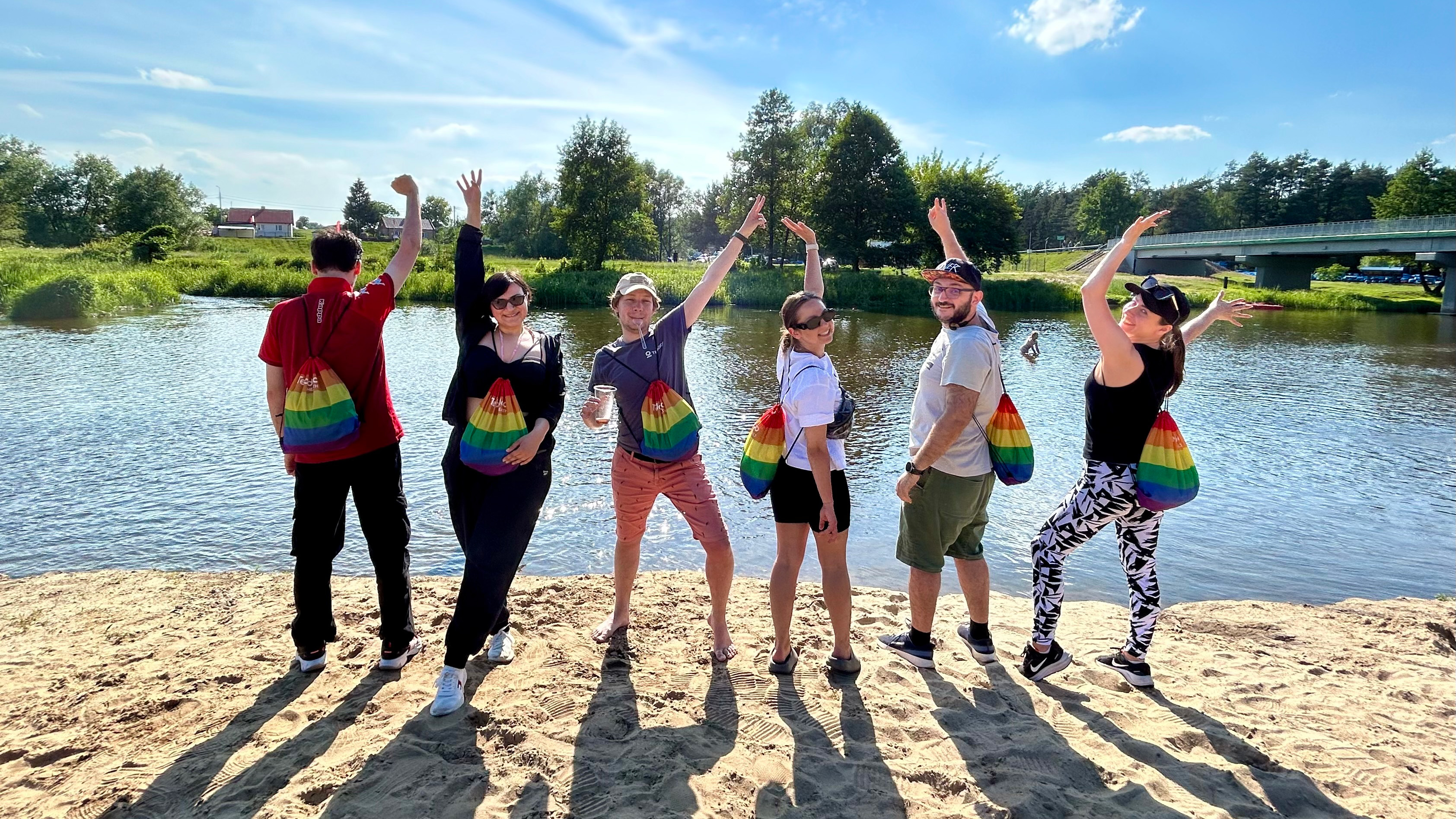 People posing with rainbow colored backpacks