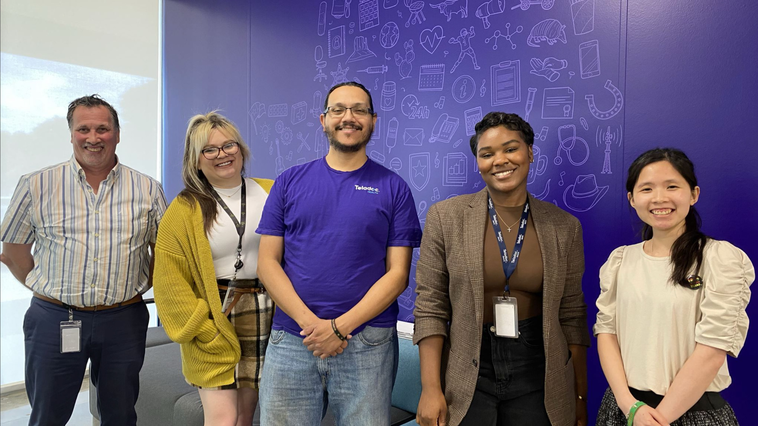 People standing in front of purple wall with icons