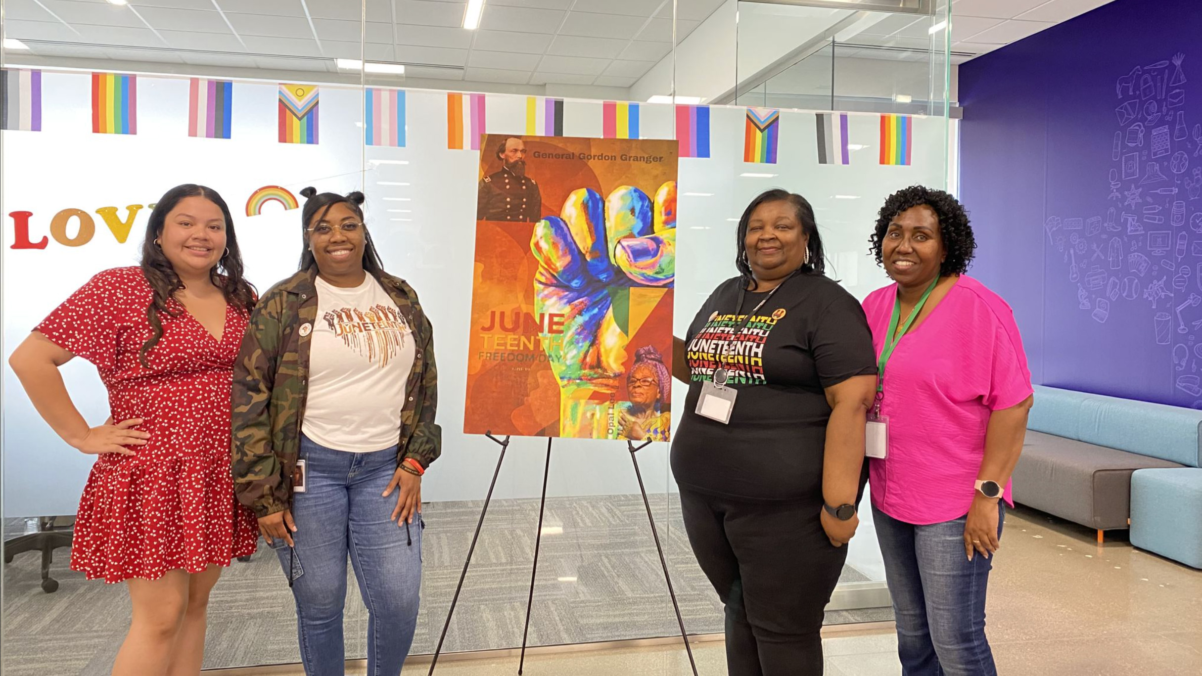 Women standing next to Juneteenth themed painting