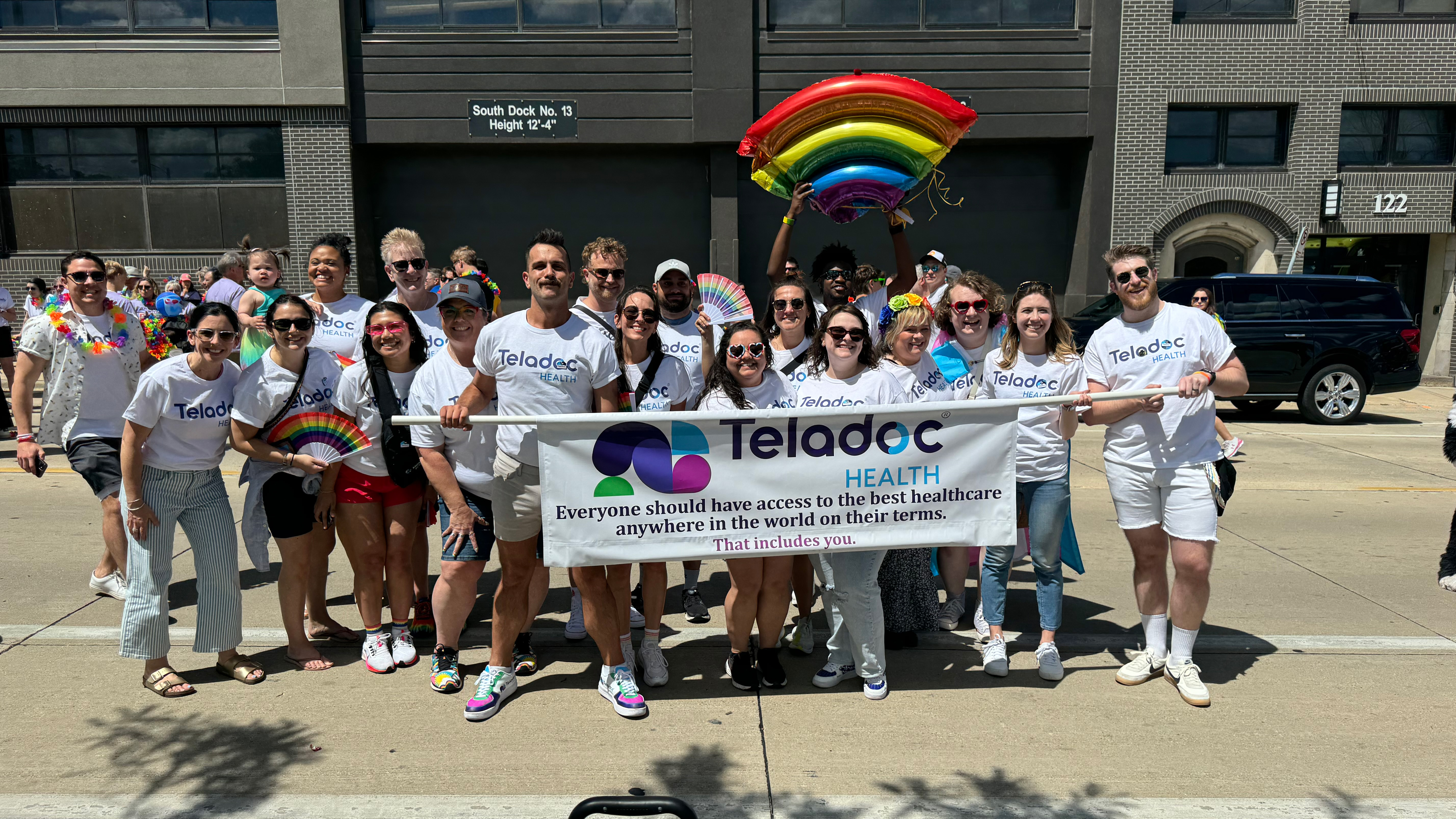 People standing with Teladoc Health banner with rainbow balloon