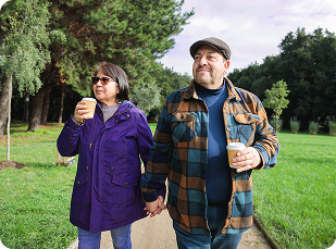 Couple walking holding hands and holding drink cups