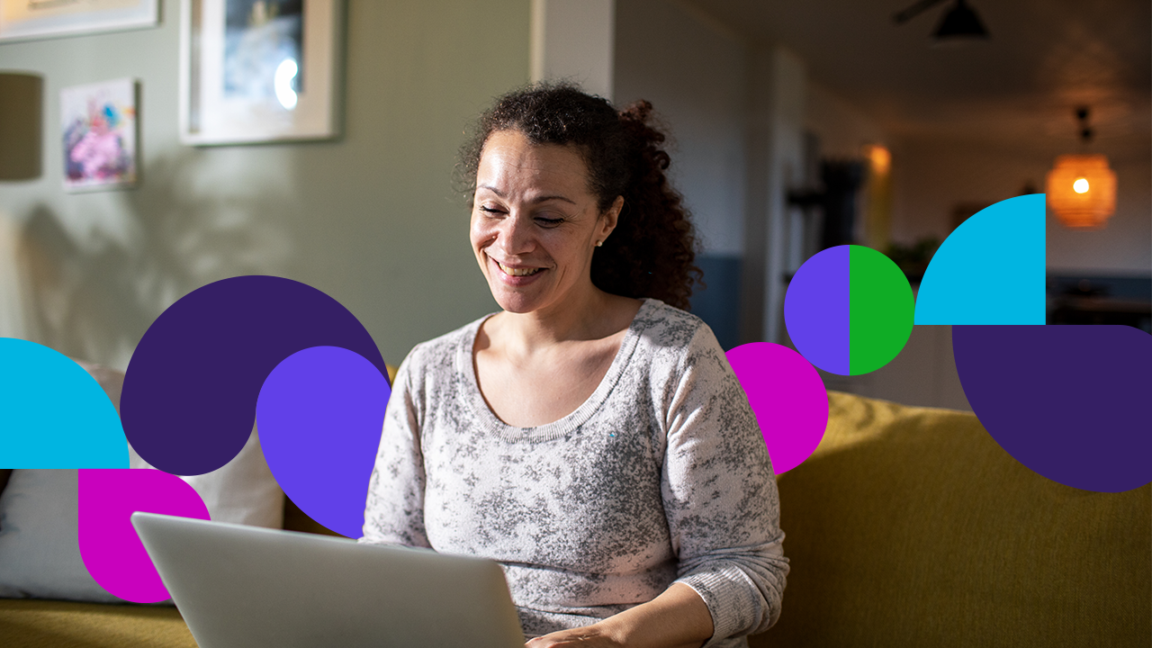 A woman looks at a computer while smiling